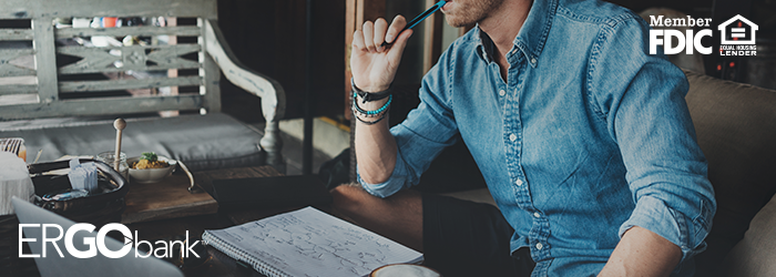 Male business owner sitting at desk with a writing pad and pen in hand