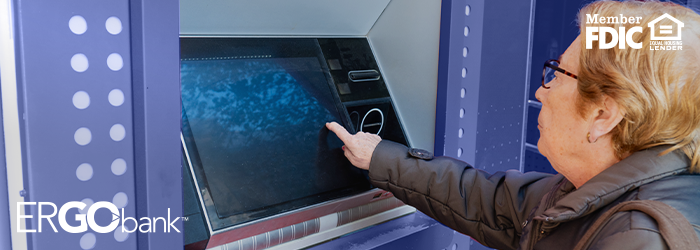 Older woman using an Ergo Bank ITM outside and tapping on the screen with her finger