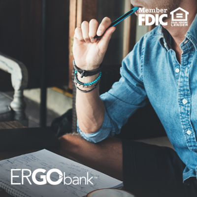 Male business owner sitting at desk with a writing pad and pen in hand